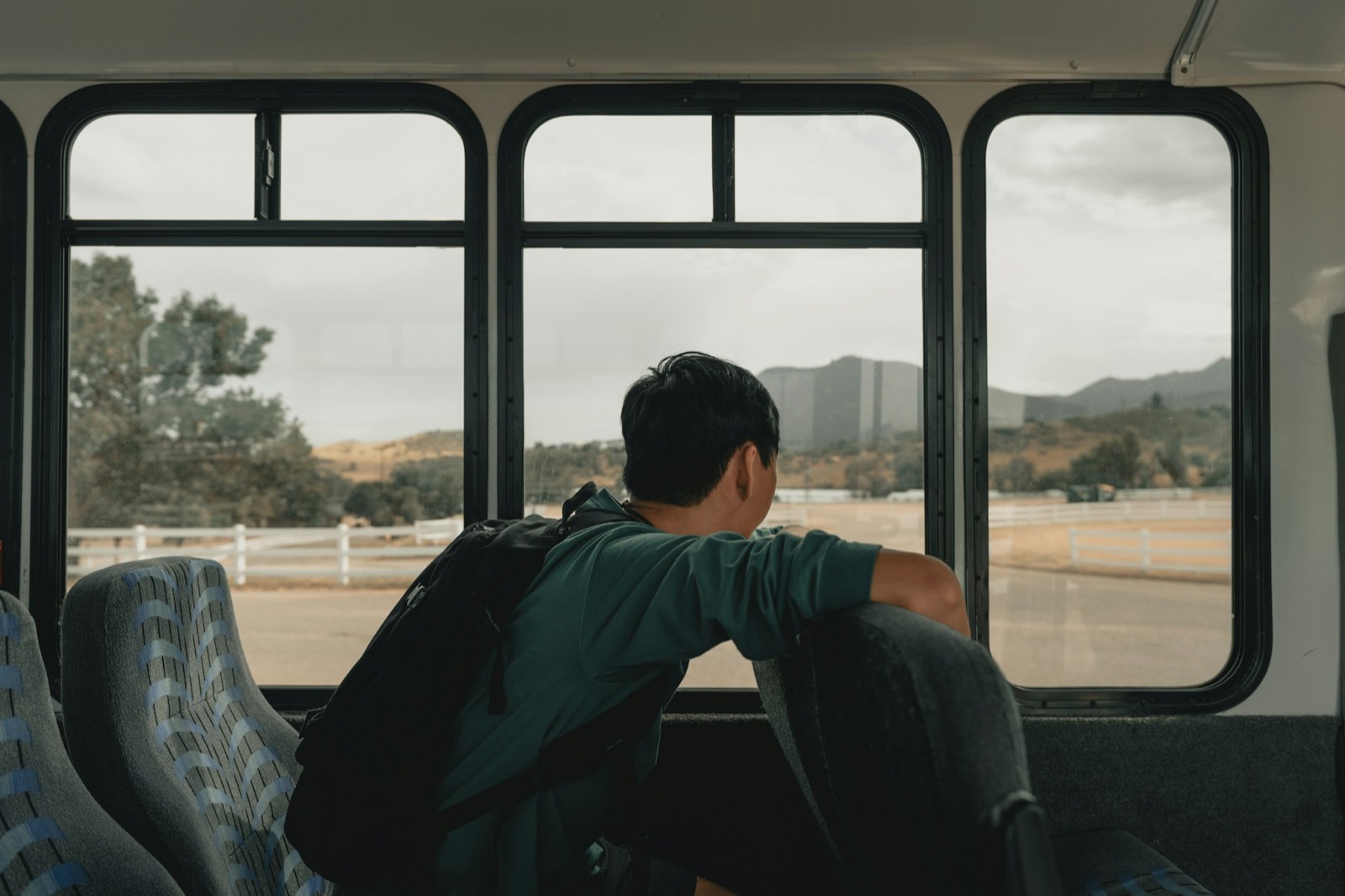 A man on a bus looking out of the window at a dry hillside