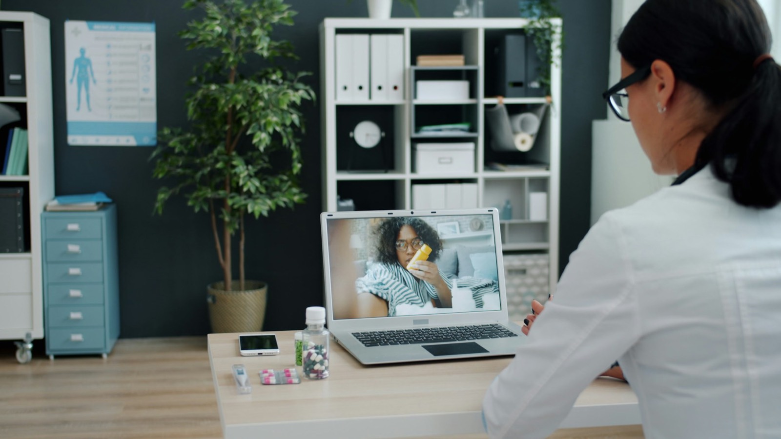 A doctor at her desk talking to a patient on a video call